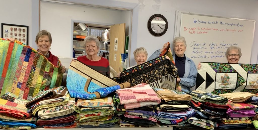 Care center support committee members with quilts from Lynden Piecable quilters