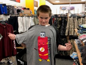 Boy showing off his new shirt at Operation School Bell event.