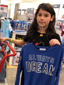 Teen showing a t-shirt she's selected that says "Always Dream"