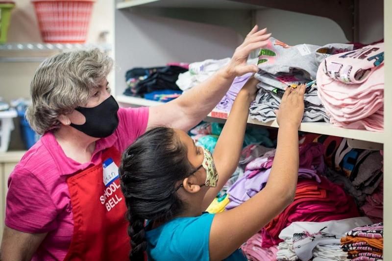 An Assistance League of Boise volunteer helps a child find the right shirt at Operaiton School Bell
