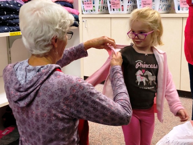 Member helping child try on new sweatshirt