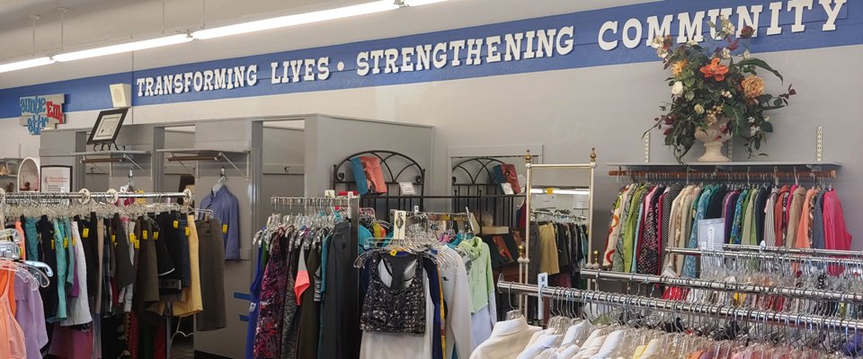 Inside of thrift shop with racks of clothing and dressing rooms