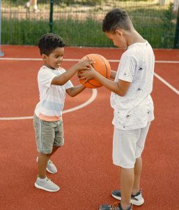 Two brothers playing basketball in basketball court together