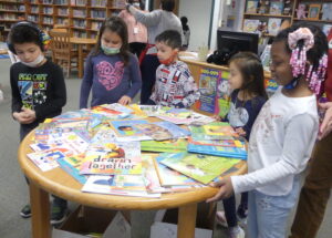 A group of children around a table of books