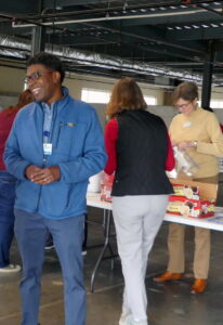 A Dominion volunteer stands in front of a table of other WFFK volunteers