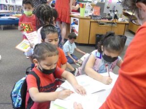 Children signing books as part of the readers and leaders event