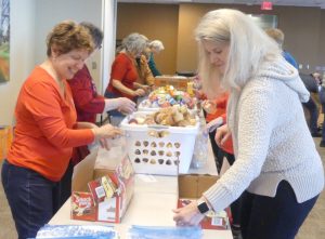 Volunteers helping to pack food items into individual donation bags