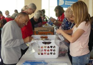 Smiling volunteers chat while packing and preparing food kits for NOVA children