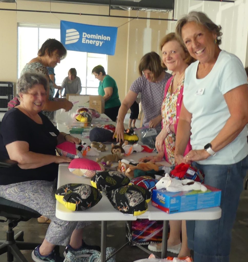 Smiling ALNV members at a packing table preparing packages for Bedtime Hugs program