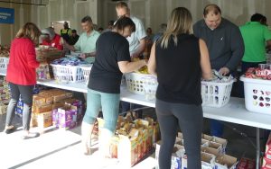 Volunteers assembling food bags for children in need