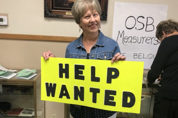 Volunteer with Help Wanted sign at OSB table - Regular Meeting