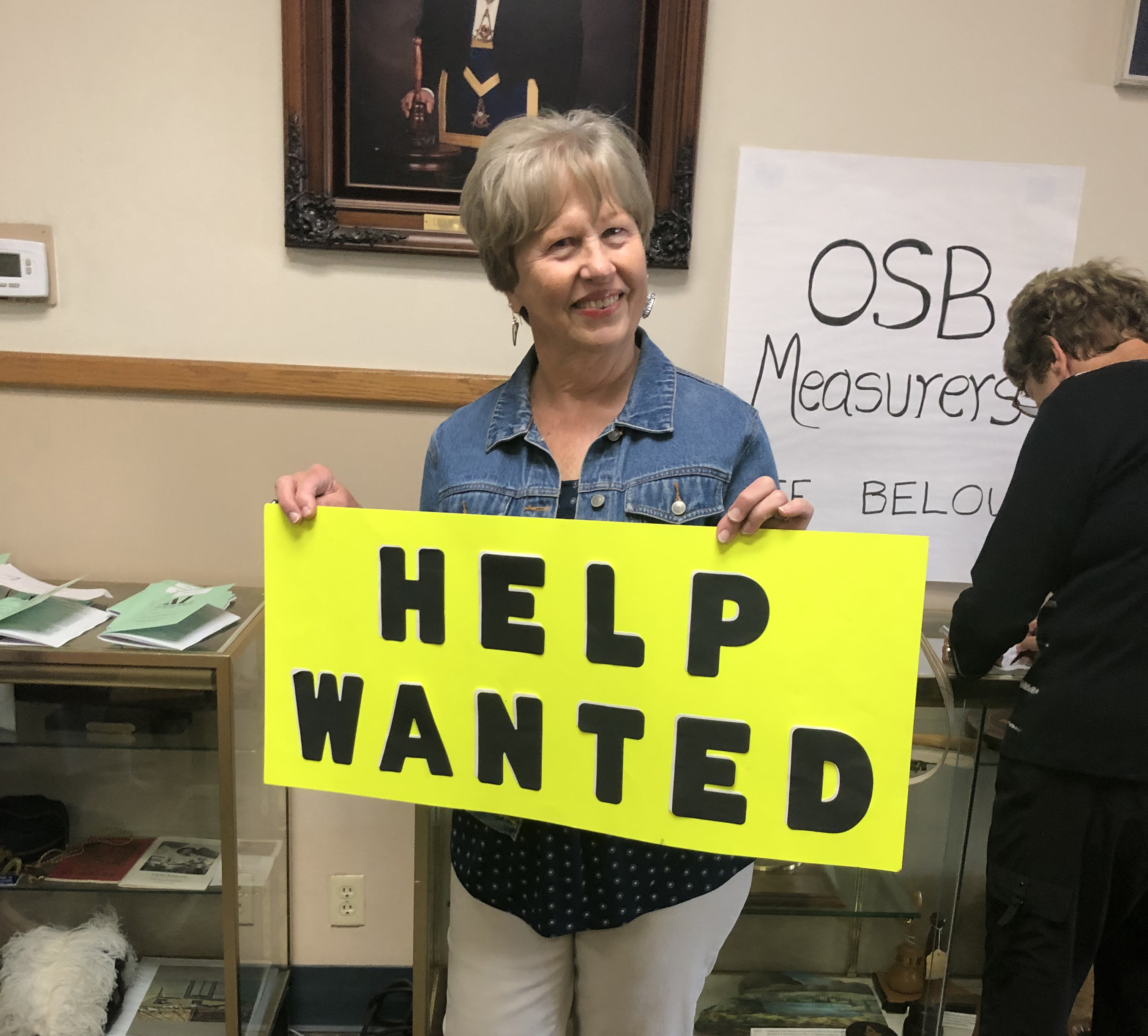 Volunteer with Help Wanted sign at OSB table - Regular Meeting