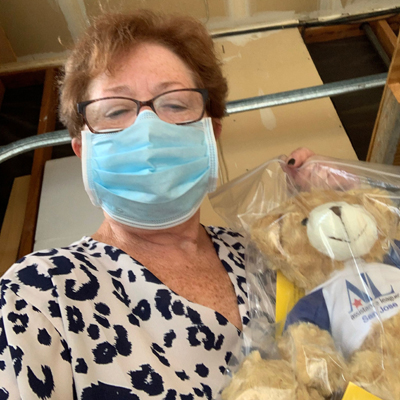 Member in face mask delivering Hug-a-Bear