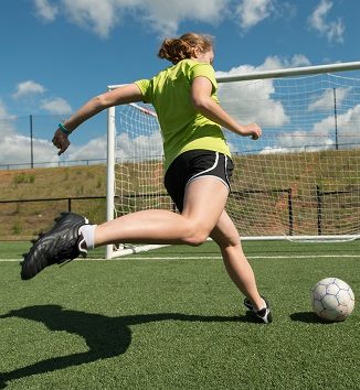 Female soccer player Young adult female soccer player practices shots on goal on a beautiful turf field