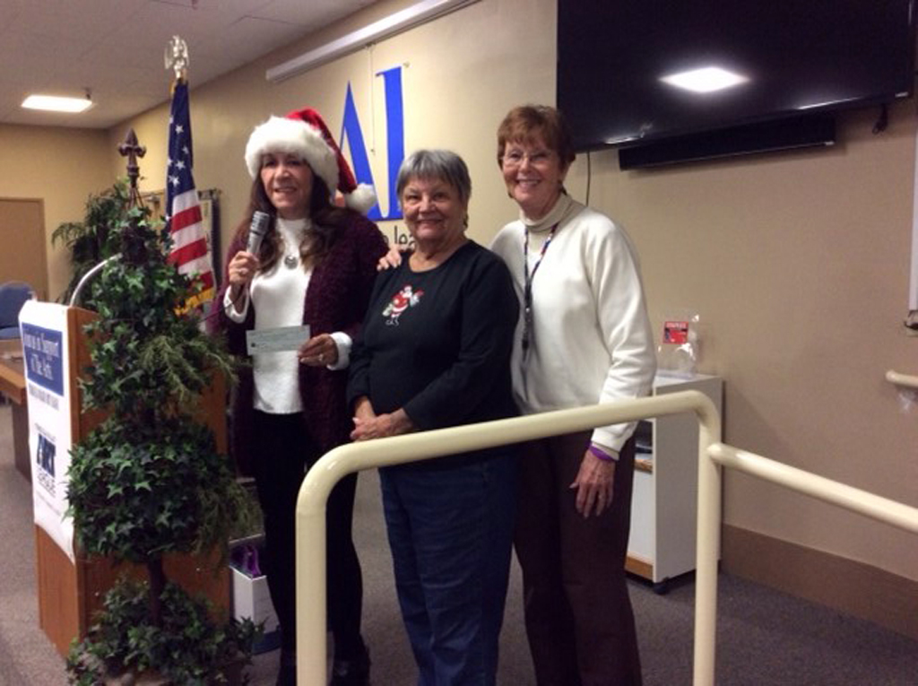 The Temecula Valley Art League’s president, Marilyn Latimer, is seen at her art group’s annual Christmas party while presenting a donation to Margo Dosky, a representative of the Assistance League of Temecula, for the Assistance League’s “Operation School Bell” charity. Debra Gayle photo