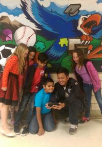 Artist Ratha Sok snaps a group selfie with Ellis Elementary students who helped design their school’s new mural.