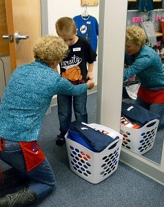 Contributed photo Assistance League of Everett volunteer Rene Porubek helps a boy pick out new clothes through the nonprofit’s Operation School Bell program in January 2016. The 2016-17 school year Operation School Bell program opens Wednesday.