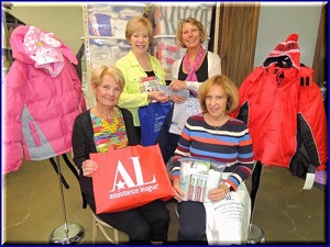 Karen Rashid-Barlow from 100 Women Who Care-Motown (standing right), presents checks to Rosemary Dirksen (standing left), Sani Dwyer, (seated left) and Cindy Guerrieri (seated right) at Assistance League's warehouse in June 2016.