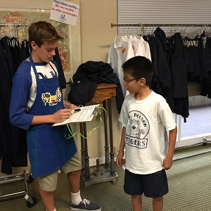 Assisteen Bradley Burdick helps a Nelson Elementary student select two school uniforms. COURTESY OF ASSISTANCE LEAGUE OF TUSTIN