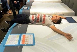 Ethan, 18, of San Bernardino, lays down on a bed he will be receiving from Ashley Furniture at the Ashley Furniture HomeStore in Colton on Thursday.