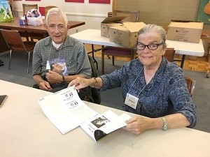 Marshall and Janice Karlin, participants in the ALF philanthropic program Retired Service Volunteers, insert labels into books, identifying them as donations to the school library by the ALF Make A Difference Day book drive.