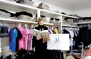 Standing in a room full of school clothes for girls, Jean Maley peruses one of the gently used books that has been donated for the Assistance League to give to a child in need. The Assistance League has been helping those in need in Roswell since 1960. (Curtis Michaels Photo)