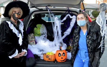 A picture containing car, 2 women giving out candy